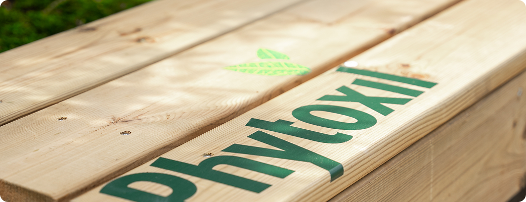 Gros plan sur le logo Phytoxil gravé sur un banc en bois clair