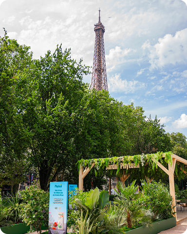 Entrée du Jardin Phytoxil nichée dans la verdure, avec la Tour Eiffel se détachant en arrière-plan